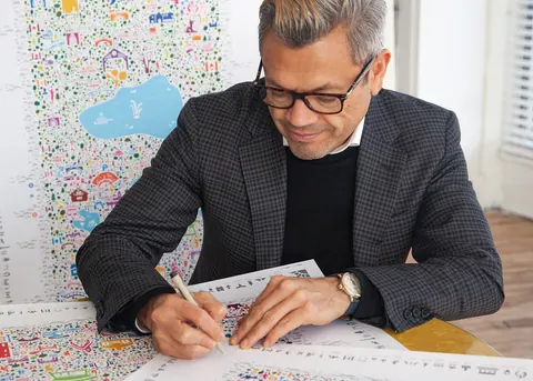 Grafikdesigner Rafael Esquer arbeitet in seinem New Yorker Studio mit Stift an einem Plakat