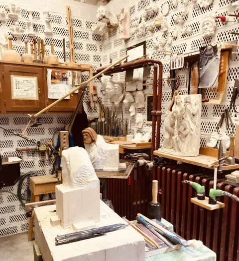 Werkstatt der Kölner Dombauhütte: Gipsmodelle an der Wand, im Vordergrund ein Steinblock mit begonnener Figur